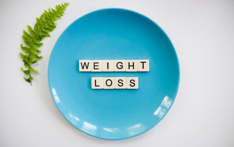 Niebieski talerz z napisem weight loss i liściem paproci na białym tle